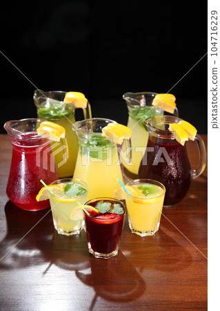 Cold lemonades. Berry Lemonade. Quenching thirst and refreshing drinks. Lemonade in the jug and lemons with mint on the table indoor. Cold lemonades. Berry Lemonade. Quenching thirst and refreshing drinks. Lemonade in the jug and lemons with mint on the table indoor. 104716229