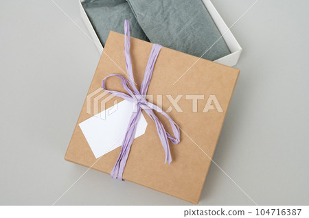 Boxes for parcels made of kraft paper on a gray background. Gift box with a tag for text, logo. Boxes for parcels made of kraft paper on a gray background. Gift box with a tag for text, logo. 104716387