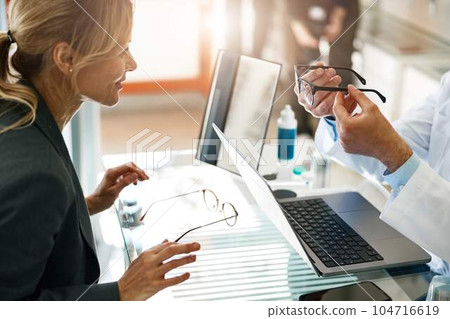 Ophthalmologist offers the client to replace the old spectacle frame with a modern one Ophthalmologist offers the client to replace the old spectacle frame with a modern one 104716619