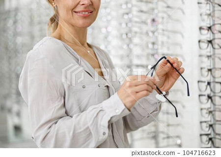 Close up of smiling woman holding a spectacle frame in her hands 104716623