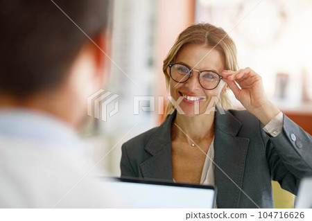 Male optometrist helping woman to choose glasses in optical store Male optometrist helping woman to choose glasses in optical store 104716626