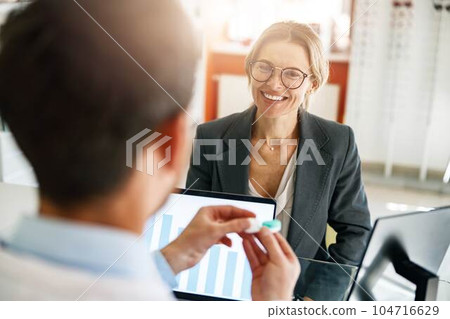 Male optometrist hands giving pair of contact lens in case to patient offering choice Male optometrist hands giving pair of contact lens in case to patient offering choice 104716629