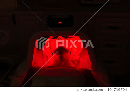 Woman getting facial treatment with led therapy. 104716704