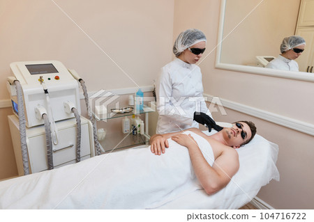 Young man receiving epilation in beauty center. laser hair removal procedure 104716722