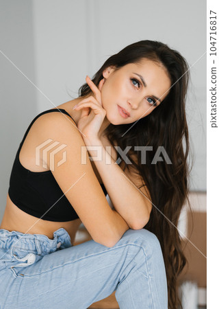 Beautiful Caucasian young woman with long hair, daytime makeup in a black top and jeans Beautiful Caucasian young woman with long hair, daytime makeup in a black top and jeans 104716817