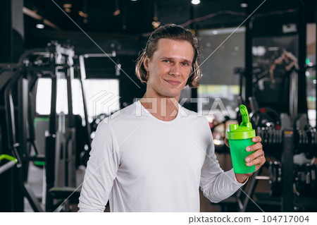 healthy sport man with whey shaker bottle. happy drinking whey protein for muscle strength mass gain and low fat beverage meal in gym fitness 104717004