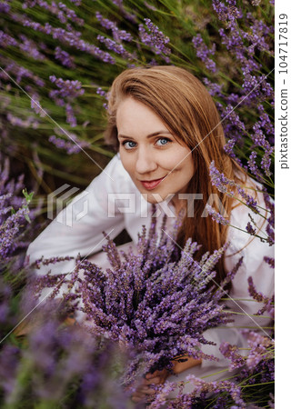 Woman Sitting among Lavender Flowers in Field 104717819