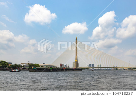 Sand boats are sailing along the Chao Phraya River. Bangkok's main river going through the Rama VIII Bridge in the daytime the sky is beautiful. It is a way of life. Sand boats are sailing along the Chao Phraya River. Bangkok's main river going through the Rama VIII Bridge in the daytime the sky is beautiful. It is a way of life. 104718227