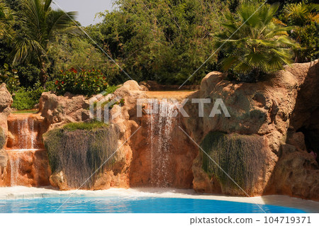 Tropical pool with waterfalls and tropical palm trees. The concept of exotic recreation 104719371
