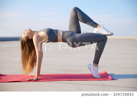 Strong, athletic young woman with slim body training in stylish sportswear ptfoors on warm sunny day. Stretching Strong, athletic young woman with slim body training in stylish sportswear ptfoors on warm sunny day. Stretching 104720093