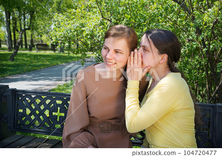 Two girls gossip in the park Two girls gossip in the park 104720477