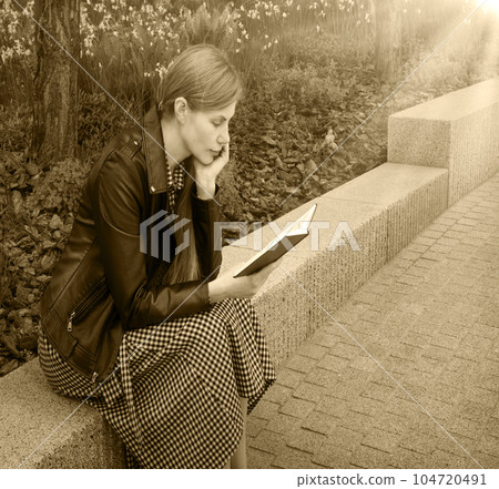Girl reading a book in the park 104720491