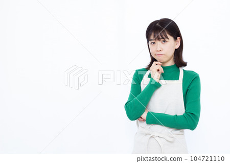 A housewife in her thirties in an apron who is in trouble in front of a white background A housewife in her thirties in an apron who is in trouble in front of a white background 104721110