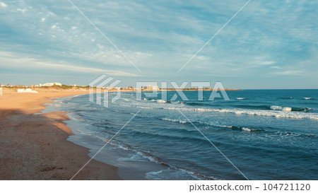 Sea waves come to the shore at sunset 104721120