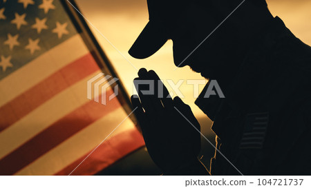 Silhouette of American soldier praying for memorial day against the flag outdoor Silhouette of American soldier praying for memorial day against the flag outdoor 104721737