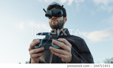 Man pilot a drone with technologic virtual reality glasses and remote controller Man pilot a drone with technologic virtual reality glasses and remote controller 104721931