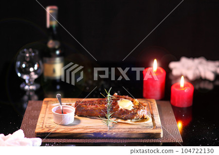 Rib eye steak on the New Year's table. Steak rib eye roast on a wooden board with sauce and salt. Beef steak on wooden plate. Rib eye steak on the New Year's table. Steak rib eye roast on a wooden board with sauce and salt. Beef steak on wooden plate. 104722130