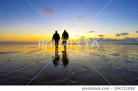 Silhouette of Two Teenage Girls Walking on Beach Under a Dramatic Sky Silhouette of Two Teenage Girls Walking on Beach Under a Dramatic Sky 104722898