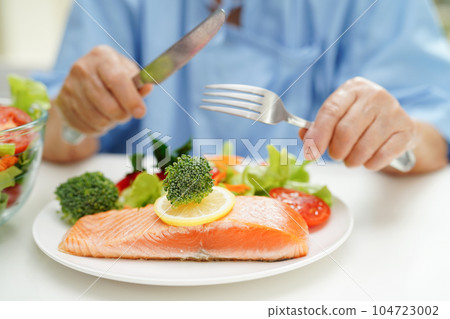 Asian elderly woman patient eating salmon stake and vegetable salad for healthy food in hospital. 104723002