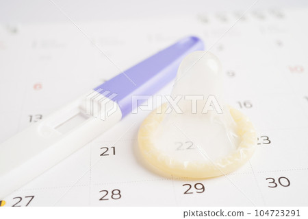 Pregnancy test and condom for female on calendar, ovulation day. Pregnancy test and condom for female on calendar, ovulation day. 104723291