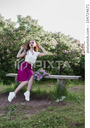 A fashionable girl with dark hair, a spring portrait in lilac tones in summer. Bright professional makeup. A fashionable girl with dark hair, a spring portrait in lilac tones in summer. Bright professional makeup. 104724671