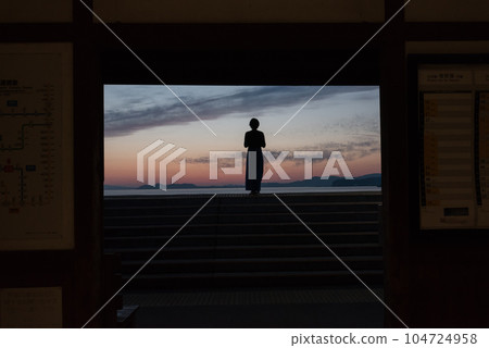 Sunset and a woman standing on the platform of JR Chiwata Station in Higashisonogi-gun, Nagasaki Prefecture 104724958
