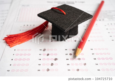 Graduation gap hat and pencil on answer sheet background, Education study testing learning teach concept. 104725710