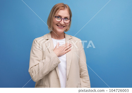 kind mature woman in a stylish image holds her hands near her heart on a bright studio background kind mature woman in a stylish image holds her hands near her heart on a bright studio background 104726003