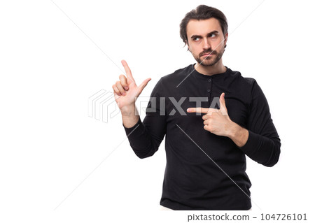 young bearded brutal european macho man with ear piercing and with black hair points his finger to young bearded brutal european macho man with ear piercing and with black hair points his finger to 104726101