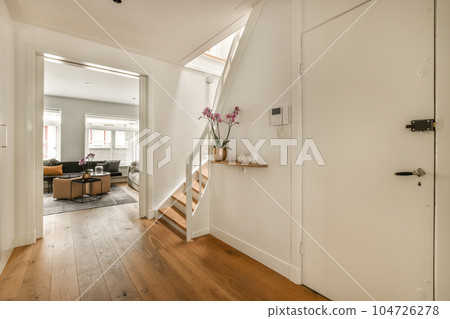 a living room with wood floors and white walls, an open door leading to the dining area is in the background 104726278