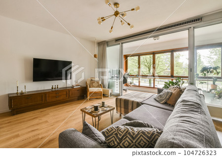 a living room with wood flooring and sliding glass doors that open onto the balcony overlooking out to the garden a living room with wood flooring and sliding glass doors that open onto the balcony overlooking out to the garden 104726323