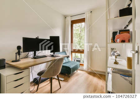 a room with a desk, chair and computer monitor on it's stand in front of a window that looks out onto the a room with a desk, chair and computer monitor on it's stand in front of a window that looks out onto the 104726327