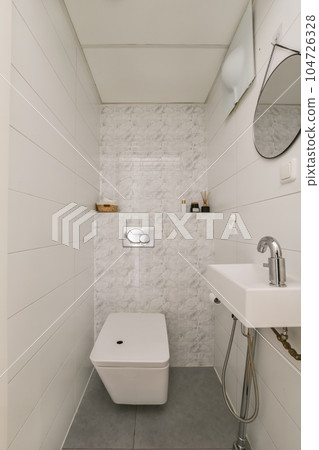 a small bathroom with a toilet and sink in the corner, white tiles on the walls and gray concrete floor a small bathroom with a toilet and sink in the corner, white tiles on the walls and gray concrete floor 104726328