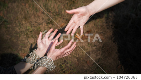 Bound hands reach out to the outstretched hand for help Bound hands reach out to the outstretched hand for help 104726363