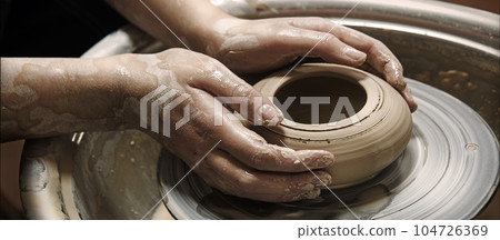 Master's hands mold a jug on a potter's wheel Master's hands mold a jug on a potter's wheel 104726369