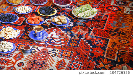 Eastern feast. Asian still life of dried fruits and nuts in plates on a carpet Eastern feast. Asian still life of dried fruits and nuts in plates on a carpet 104726526