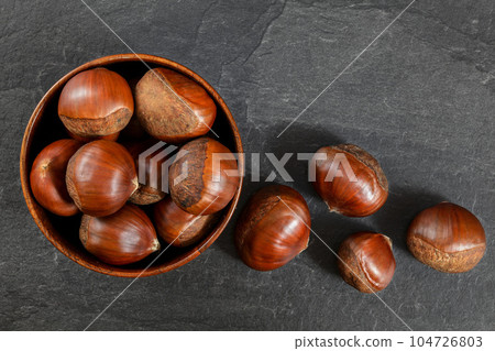 Top down view, small bowl with chestnuts on black slate board Top down view, small bowl with chestnuts on black slate board 104726803