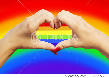Womans hands making heart sign with gay pride LGBT rainbow flag Womans hands making heart sign with gay pride LGBT rainbow flag 104727228