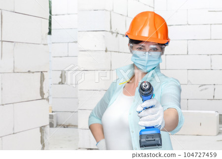 The master holds a drill in his hands in a mask. 104727459