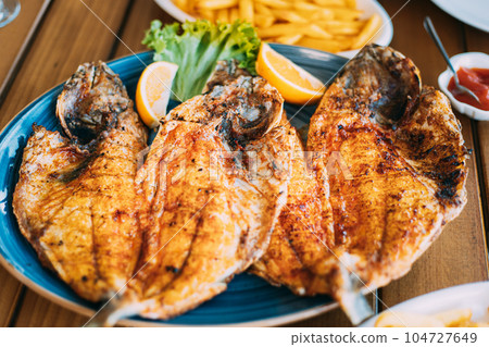 Dish with Gilt-head bream Fish With orange and french fries. Dorada, Dorade, dorado, Dourada fish and chips Dish with Gilt-head bream Fish With orange and french fries. Dorada, Dorade, dorado, Dourada fish and chips 104727649