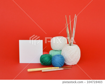 A closeup shot of red, purple, and blue knitting yarns and crochet hooks 104728483