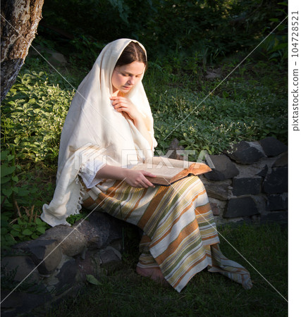Young girl in ancient clothes reads a book 104728521