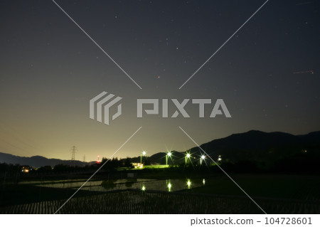 夜幕降臨，北斗市竹川町，舞鶴橋上空升起紅星心宿二。戶外的燈光倒映在稻田裡 104728601