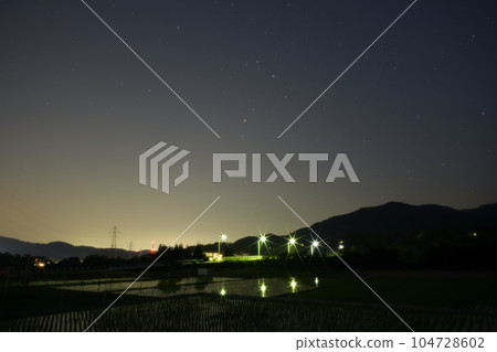 夜幕降臨，北斗市竹川町，舞鶴橋上空升起紅星心宿二。戶外的燈光倒映在稻田裡 104728602