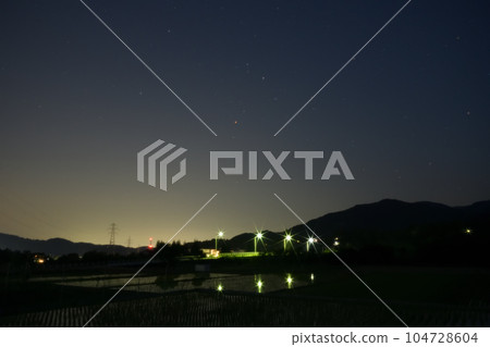 夜幕降臨，北斗市竹川町，舞鶴橋上空升起紅星心宿二。戶外的燈光倒映在稻田裡 104728604