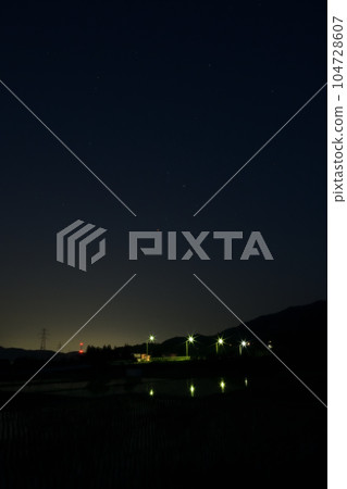 夜幕降臨，北斗市竹川町，舞鶴橋上空升起紅星心宿二。戶外的燈光倒映在稻田裡 104728607