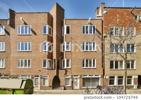 an apartment building with bicycles parked on the sidewalk next to it and two buildings in the background are bricked an apartment building with bicycles parked on the sidewalk next to it and two buildings in the background are bricked 104728749