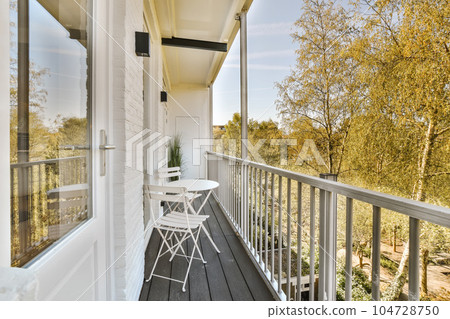 a balcony with chairs and trees in the background on a sunny day, taken from an open window looking outside a balcony with chairs and trees in the background on a sunny day, taken from an open window looking outside 104728750