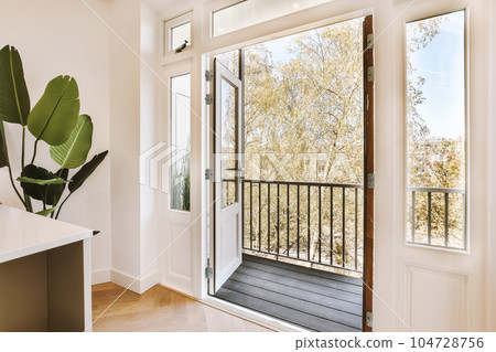an open door with a plant in the middle and a window on the other side that has a view of trees outside 104728756