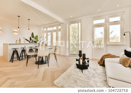 a living room with hardwood flooring and white furniture in the center of the room is an open dining area 104728758